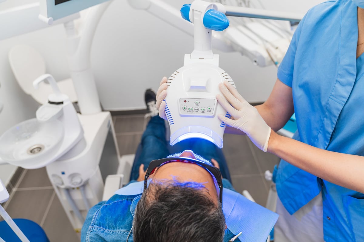 Professional dentist performing teeth whitening treatment with patient smiling at Galleon Way Dental