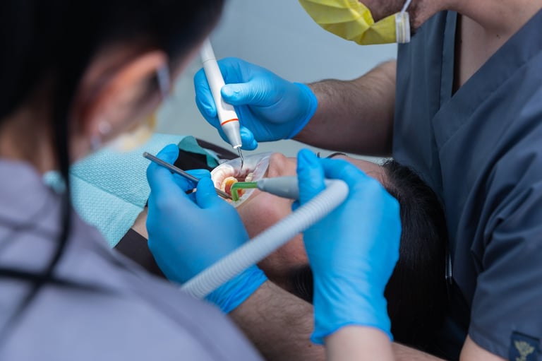 This image showcases a dental procedure where a patient is receiving care from two dental professionals, illustrating the use of modern tools and the importance of teamwork in dentistry.