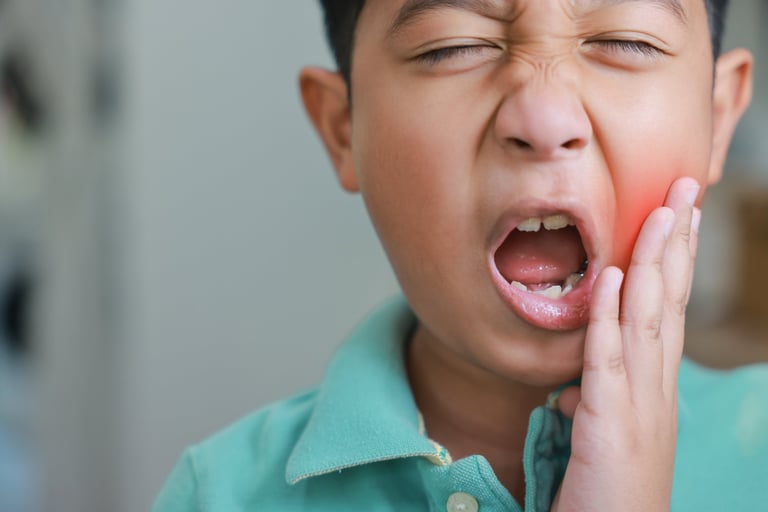 Asian boy suffering from severe toothache with red highlight on cheek, child having dental problem, tooth decay, gum inflammation, sensitive teeth or wisdom tooth pain and crying at home.