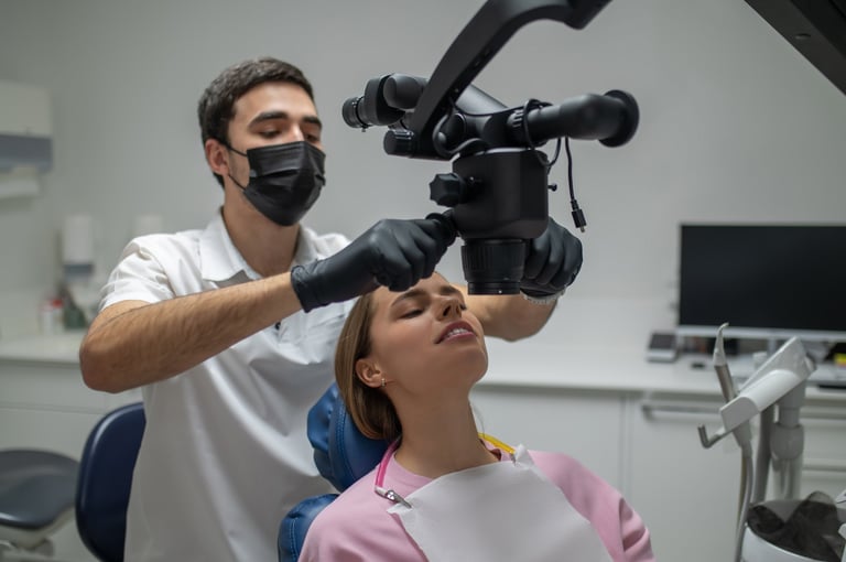 Professional specialist performing dental surgery with microscope for young woman in medical clinic